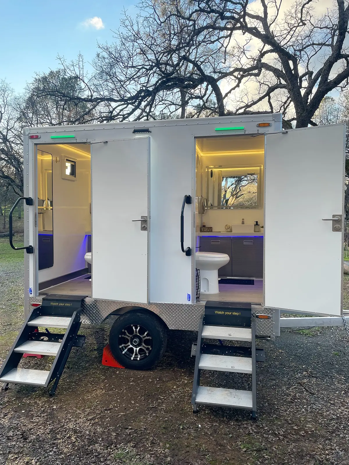 Lit restroom trailer with steps and open doors